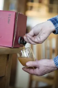Apfelsaft wird aus der Saftbox in ein Glas gezapft
